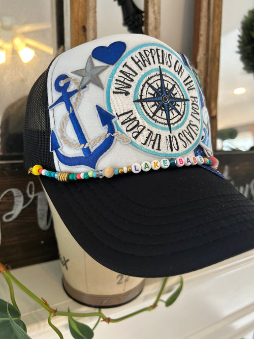 black and white trucker hat with compass, martini, wave, large star, and anchor iron patch 