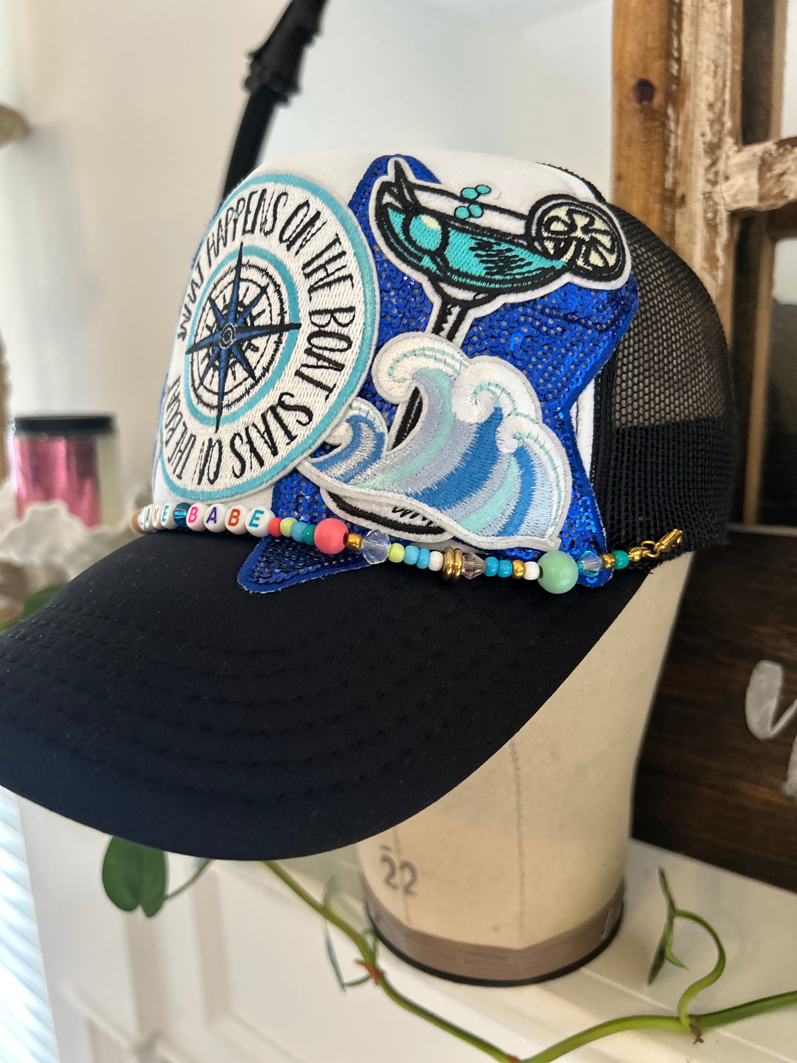 black and white trucker hat with compass, martini, wave, large star, and anchor iron patch 